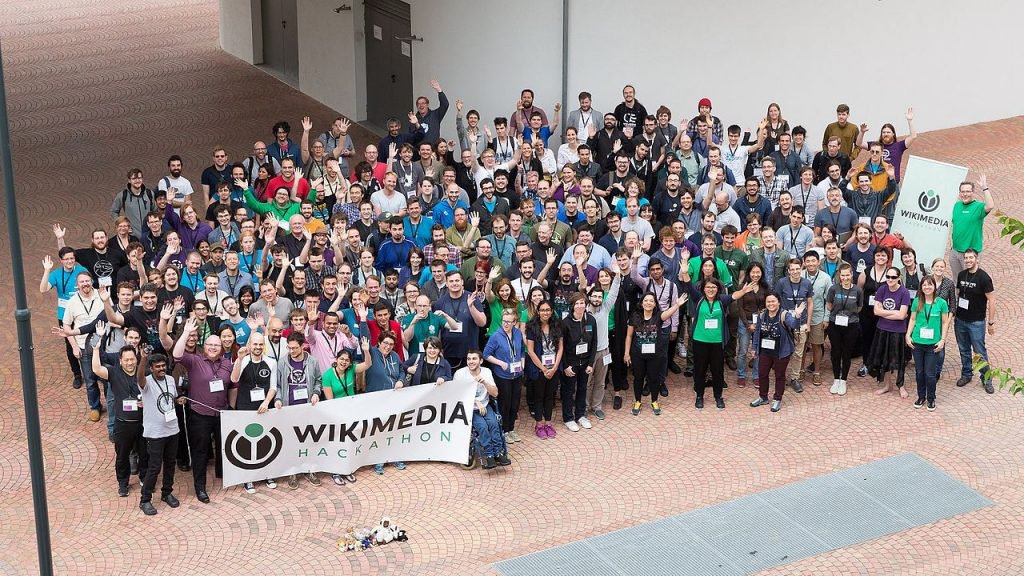 Groupe de Wikimédiennes et Wikimédiens tenant une bannière "Wikimedia Hackathon"